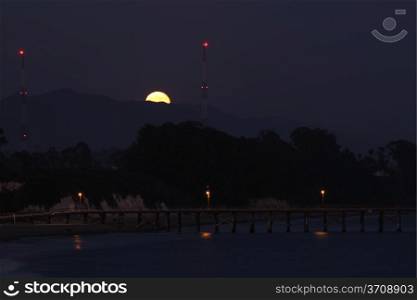 Full moon rising over the Goleta pier near Santa Barbara.