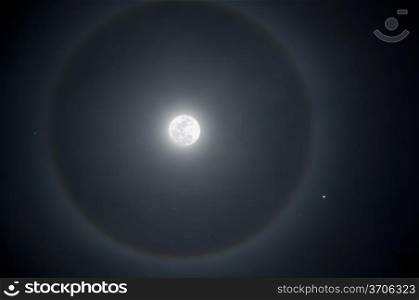 Full moon with a ring of ice in the atmosphere. A crescent moon next to a star.