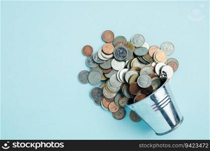Full of money coins in a tin bucket on blue background for investment, business, finance and saving money concept 