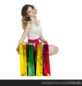 Full portrait of smiling young blonde girl with colorful shopping bags in red skirt posing on a white background