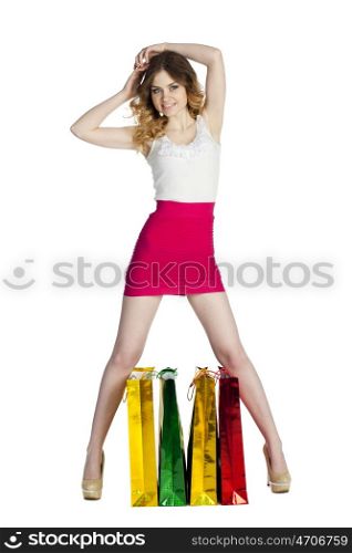 Full portrait of smiling young blonde girl with colorful shopping bags in red skirt posing on a white background