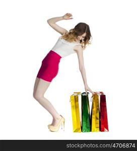 Full portrait of smiling young blonde girl with colorful shopping bags in red skirt posing on a white background