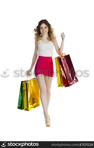 Full portrait of smiling young blonde girl with colorful shopping bags in red skirt posing on a white background