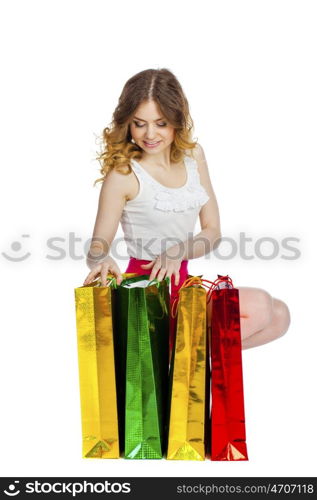 Full portrait of smiling young blonde girl with colorful shopping bags in red skirt posing on a white background