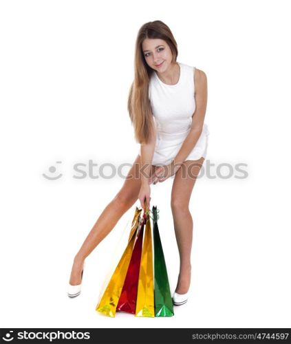 Full portrait of smiling young blonde girl with colorful shopping bags in white dress posing on a white background