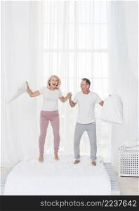 full shot couple jumping bed