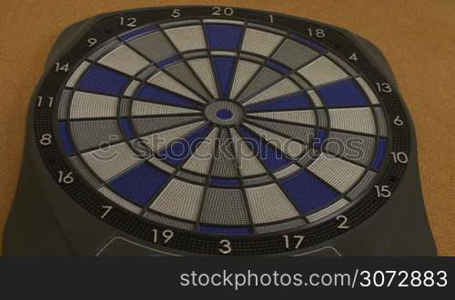 Full shot of electronic dartboard with dart finally hitting bullseyes at the third and last one