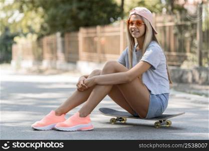 full shot smiley girl sitting skateboard
