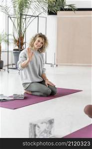 full shot smiley woman sitting yoga mat