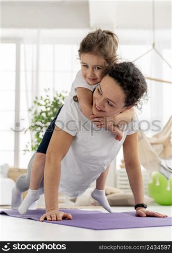 full shot woman doing plank with kid