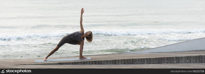 full shot woman doing triangle pose beach