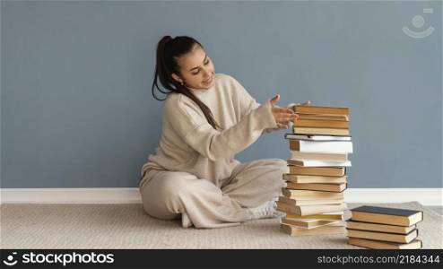 full shot woman stacking books