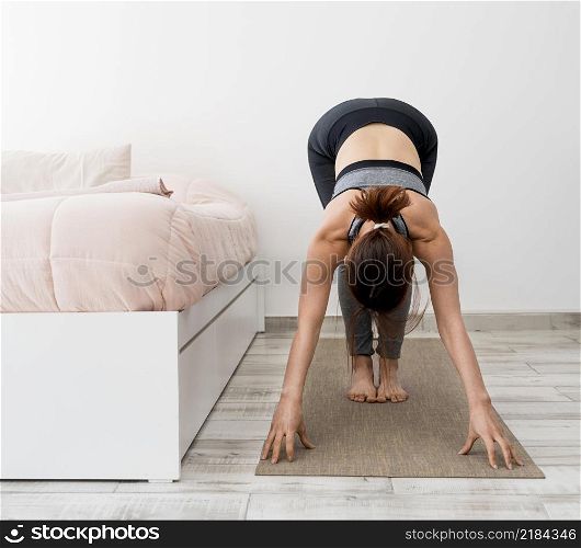 full shot woman stretching mat home