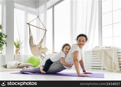 full shot woman stretching with kid 2