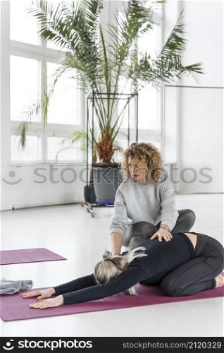 full shot woman stretching with teacher