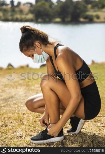 full shot woman with mask tying shoelaces