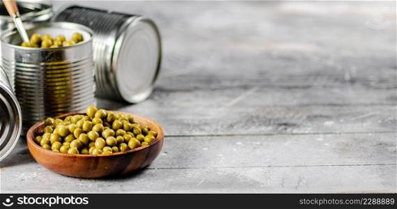 Full wooden plate with canned green peas. On a gray background. High quality photo. Full wooden plate with canned green peas.