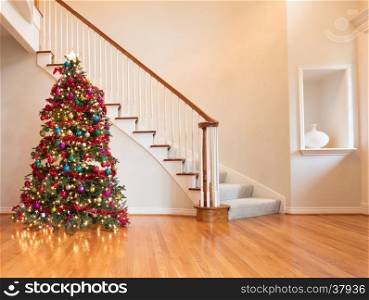 Fully decorated Christmas on wooden floor with staircase in background