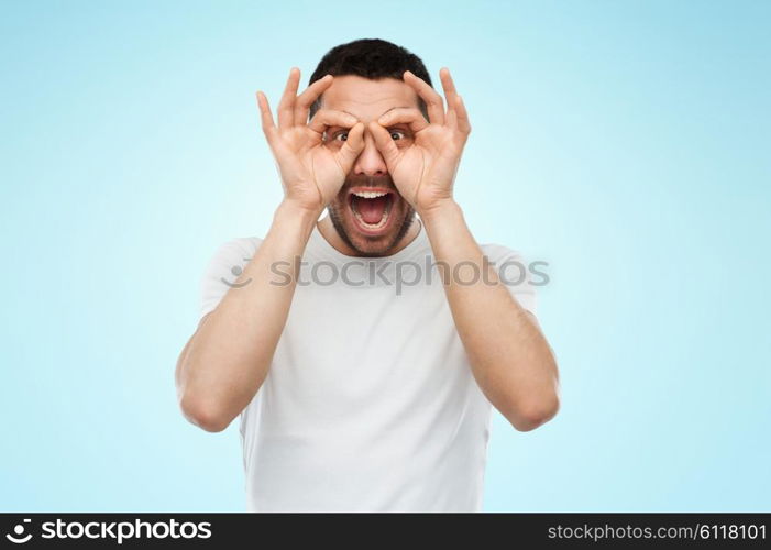 fun and people concept - man making finger glasses over blue background. man making finger glasses over blue background