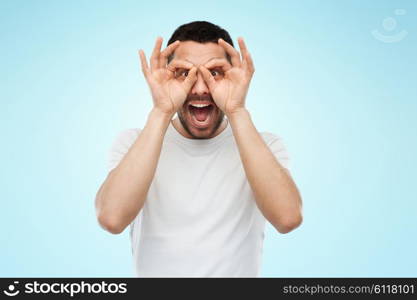 fun and people concept - man making finger glasses over blue background. man making finger glasses over blue background