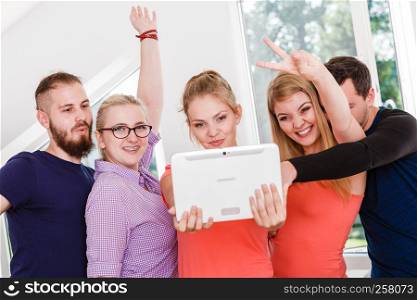 Fun bonding selfie concept. Group of diverse friends students classmates taking self photo with tablet pc computer indoors in class. friends students taking self photo with tablet