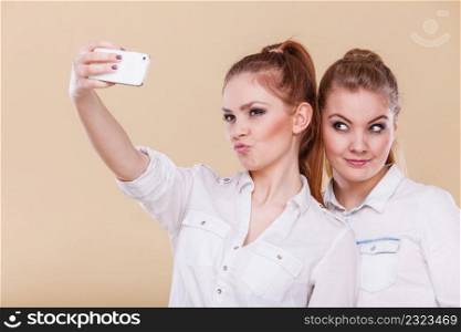 Fun bonding selfie concept. Sisters or best friends, two student blonde girls taking self photo with smart phone camera, having fun, positive funny emotion on face. friends student girls taking self photo with smart phone