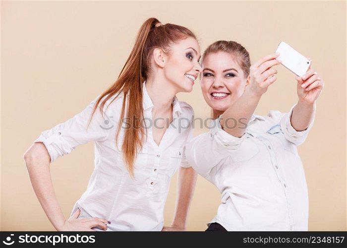 Fun bonding selfie concept. Sisters or best friends, two student blonde girls taking self photo with smart phone camera, having fun, positive funny emotion on face. friends student girls taking self photo with smart phone