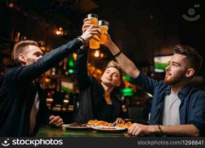 Fun company raised their glasses with beer in a sport bar, happy football fans. Fun company raised their glasses in a sport bar