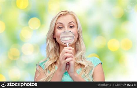 fun, emotions, expressions and people concept - happy smiling young woman or teenage girl having fun with magnifying glass over summer green lights background