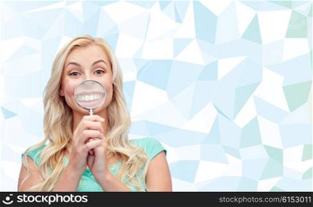fun, emotions, expressions and people concept - happy smiling young woman or teenage girl having fun with magnifying glass over blue low poly background