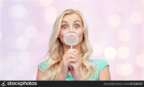 fun, emotions, expressions and people concept - happy smiling young woman or teenage girl having fun with magnifying glass over pink holidays lights background