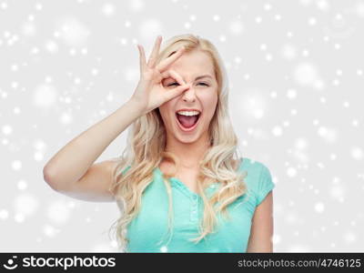 fun, emotions, expressions and people concept - smiling young woman or teenage girl making ok hand gesture over snow