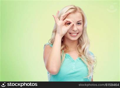 fun, emotions, expressions and people concept - smiling young woman or teenage girl making ok hand gesture over green natural background