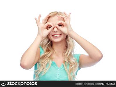 fun, emotions, expressions and people concept - smiling young woman or teenage girl looking through glasses made of fingers