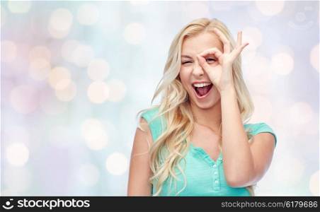 fun, emotions, expressions and people concept - smiling young woman or teenage girl making ok hand gesture over holidays lights background