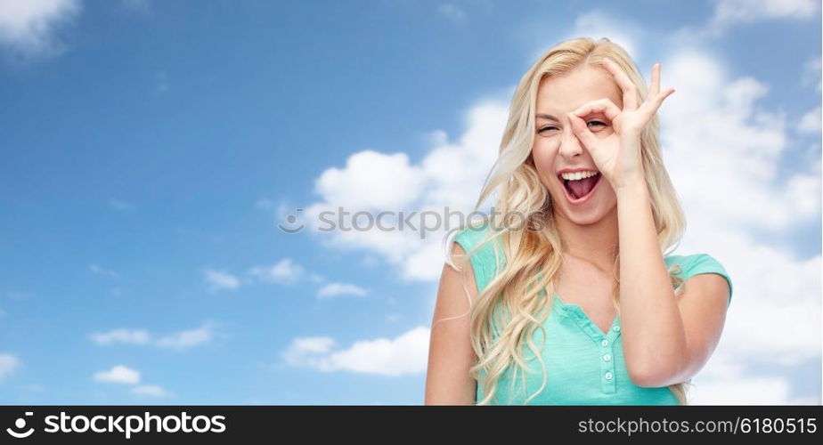 fun, emotions, expressions and people concept - smiling young woman or teenage girl making ok hand gesture over blue sky and clouds background