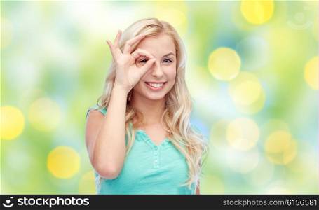 fun, emotions, expressions, summer and people concept - smiling young woman or teenage girl making ok hand gesture over green lights background