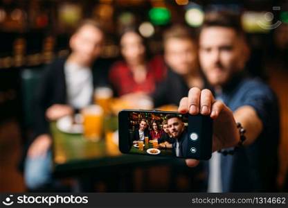 Fun friends makes selfie on phone camera in a sport bar, happy leisure of football fans. Fun friends makes selfie on phone in a sport bar