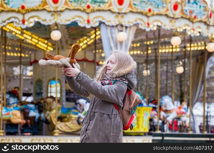 fun girl with a toy dog on the background of the French carousel. Paris, France