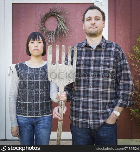 Fun Mixed Race Couple Portrait Simulating the American Gothic Painting by Grant Wood.