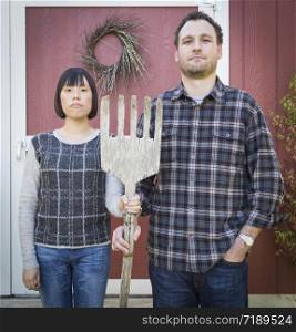 Fun Mixed Race Couple Portrait Simulating the American Gothic Painting by Grant Wood.