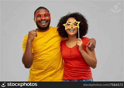 fun, photo booth and people concept - happy african american couple with party props hugging over grey background. happy african american couple with party props