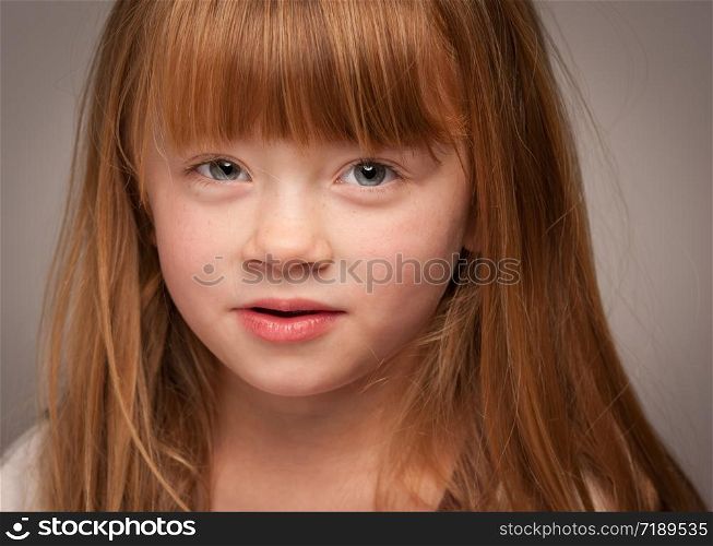 Fun Portrait of an Adorable Red Haired Girl on a Grey Background.