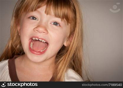 Fun Portrait of an Adorable Red Haired Girl on a Grey Background.