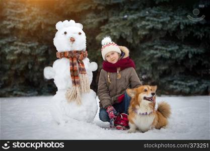 fun walk. Snowman, beautiful blond girl and corgi fluffy at the winter day