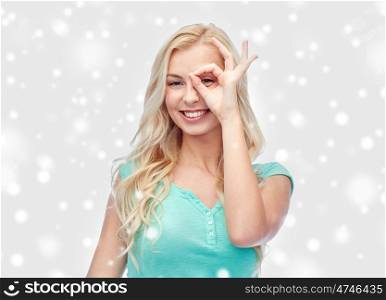 fun, winter holidays and people concept - smiling young woman or teenage girl making ok hand gesture over snow