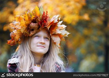 fun young girl at the park with diadem from yellow maple leaves