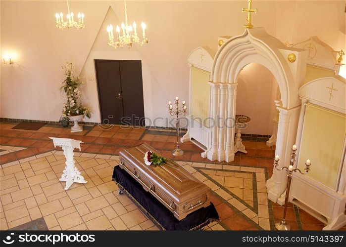 funeral and mourning concept - coffin with flowers and stand in church. coffin with flowers and stand at funeral in church