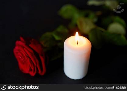 funeral and mourning concept - red rose and burning candle over black background. red rose and burning candle over black background