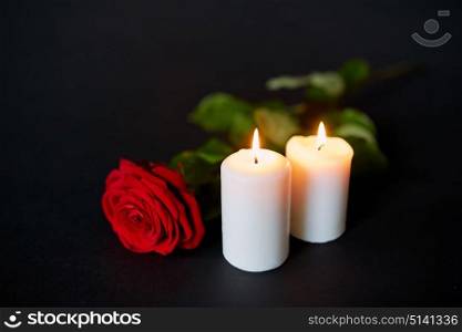 funeral and mourning concept - red rose and burning candles over black background. red rose and burning candles over black background